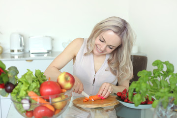 young positive smiling woman with vegetables in the kitchen