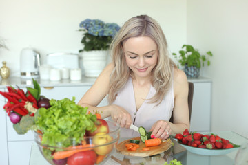 young positive smiling woman with vegetables in the kitchen