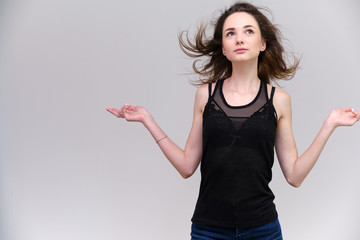 Fototapeta na wymiar Life is a success. I am pleased with myself. Concept photo of a happy smiling woman satisfied life contented brunette girl in a black T-shirt and jeans on a gray background with flowing hair.