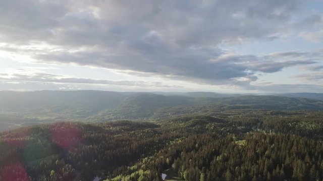 4K aerial with backward motion of the forest, valleys, cloudy blue sky and nature outside the Oslo city line in a beautiful and colorful sunset.