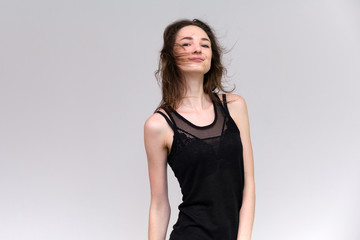 Fototapeta premium Life is a success. I am pleased with myself. Concept photo of a happy smiling woman satisfied life contented brunette girl in a black T-shirt and jeans on a gray background with flowing hair.