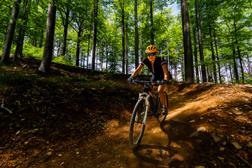 Mountain biking woman riding on bike in summer mountains forest landscape. Woman cycling MTB flow trail track. Outdoor sport activity.