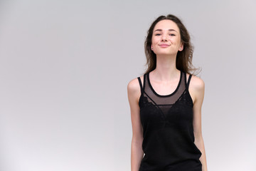 Life is a success. I am pleased with myself. Concept photo of a happy smiling woman satisfied life contented brunette girl in a black T-shirt and jeans on a gray background with flowing hair.