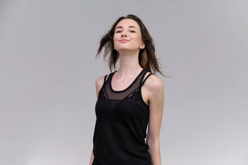 Fototapeta premium Life is a success. I am pleased with myself. Concept photo of a happy smiling woman satisfied life contented brunette girl in a black T-shirt and jeans on a gray background with flowing hair.