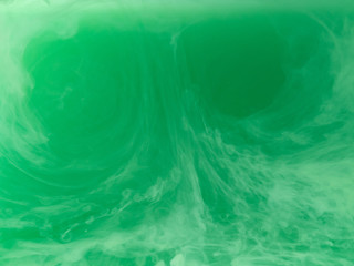 Abstract green pattern. Close up view. Blurred background. Acrylic paint dropped into liquid, abstract background. Ink waves in liquid. Acrylic smoke under water. Abstract art