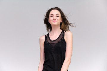 Life is a success. I am pleased with myself. Concept photo of a happy smiling woman satisfied life contented brunette girl in a black T-shirt and jeans on a gray background with flowing hair.