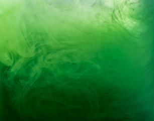 Fototapeta na wymiar Abstract green smoke under water, blurred background. Close up view. Paint dissolving into water, abstract background. Acrylic clouds in liquid. Background for abstract wallpapers and banners