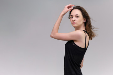 Life is a success. I am pleased with myself. Concept photo of a happy smiling woman satisfied life contented brunette girl in a black T-shirt and jeans on a gray background with flowing hair. © Вячеслав Чичаев
