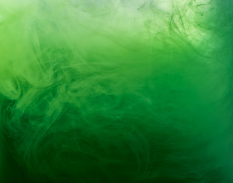Abstract green smoke under water, blurred background. Close up view. Paint dissolving into water, abstract background. Acrylic clouds in liquid. Background for abstract wallpapers and banners