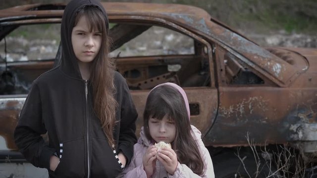 Orphans eat bread. Child loneliness. Sad little girls at the junkyard. Children after the war.