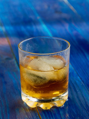 A glass of strong alcohol with ice in a transparent glass