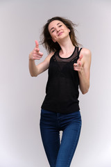 Life is a success. I am pleased with myself. Concept photo of a happy smiling woman satisfied life contented brunette girl in a black T-shirt and jeans on a gray background with flowing hair.