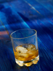 A glass of strong alcohol with ice in a transparent glass