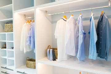 white modern wardrobe with black and blue cloth hanging. 