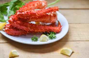 Alaskan King Crab Legs cooked seafood with lemon spices on white plate in the wooden table - red crab hokkaido