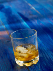 A glass of strong alcohol with ice in a transparent glass