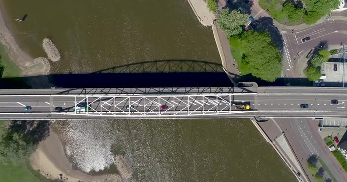 4k Aerial drone shot flying above the Wilhelmina bridge along with the traffic crossing the river the IJssel in to the town of the old Dutch Hanza city Deventer.
