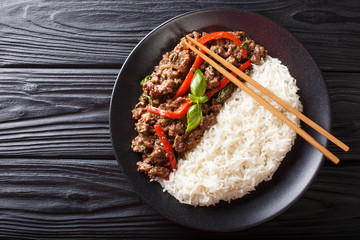 Delicious basil beef with bell peppers, garlic and onions served with rice closeup on a plate. horizontal top view
