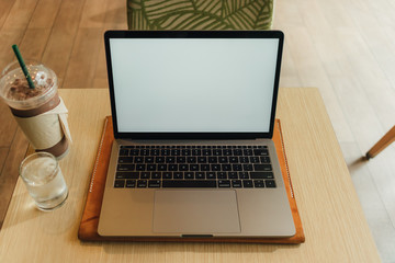 Fototapeta premium Laptop in the coffee cafe with white empty display.