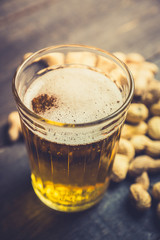 Glass of beer on the dark rustic wooden background. Selective focus. Shallow depth of field.