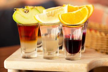 Set of shots alcohol drinks in glasses on wooden table. A set of layered cocktails in glasses(shooters) for an alcoholic party.