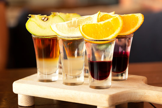 Set Of Shots Alcohol Drinks In Glasses On Wooden Table. A Set Of Layered Cocktails In Glasses(shooters) For An Alcoholic Party.