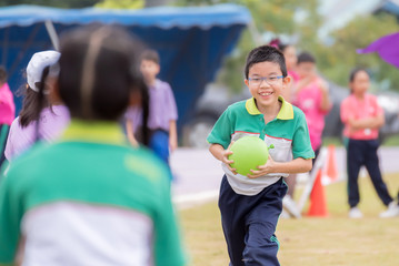 boy runs in the lawn during the competition, holding a green ballon.