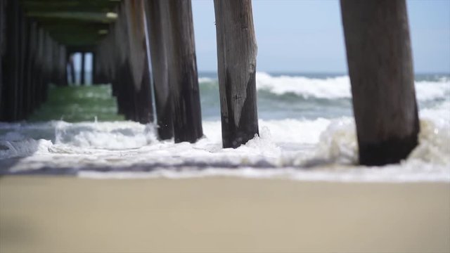 Waves crashing under a pier