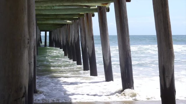 Waves crashing under a pier.