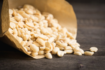 Salted peanuts in the vellum paper on rustic background. Selective focus. Shallow depth of field.