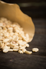 Salted peanuts in the vellum paper on rustic background. Selective focus. Shallow depth of field.