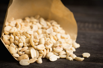 Salted peanuts in the vellum paper on rustic background. Selective focus. Shallow depth of field.