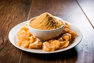 Organic Gur or Jggery Powder is unrefined sugar obtained from concentrated sugarcane juice. served in a bowl. selective focus