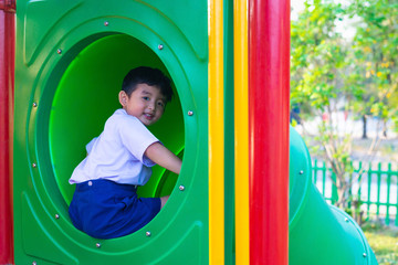 Asian kid playing slide at the playground under the sunlight in summer, Happy kid in kindergarten.