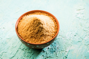 Organic Gur or Jggery Powder is unrefined sugar obtained from concentrated sugarcane juice. served in a bowl. selective focus