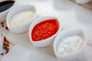 Different dips and sauces - red, white and black over white table. - 270143888