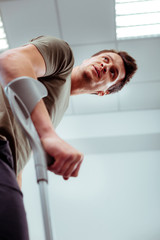 Nice young man using crutches for walking