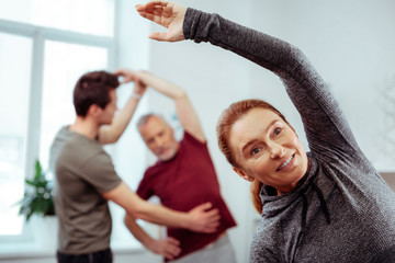 Obraz premium Joyful nice positive woman doing physical exercises