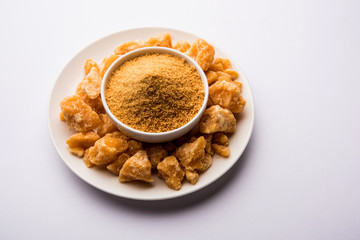 Organic Gur or Jggery Powder is unrefined sugar obtained from concentrated sugarcane juice. served in a bowl. selective focus