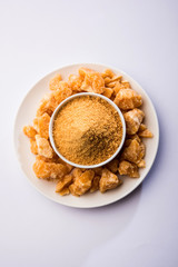 Organic Gur or Jggery Powder is unrefined sugar obtained from concentrated sugarcane juice. served in a bowl. selective focus