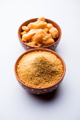 Organic Gur or Jggery Powder is unrefined sugar obtained from concentrated sugarcane juice. served in a bowl. selective focus