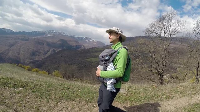 Travel with baby in Armenia. Father carries his infant son in a baby carrier, hiking in the mountains, Ijevan, Armenia.