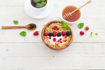 granola with berries on white wooden background