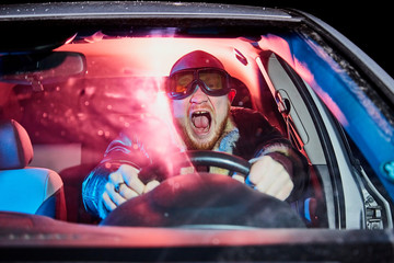 Male driver in a leather jacket in the car in the dark time. Night unusual photo shoot. Night photo...