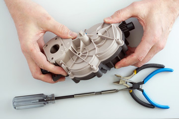 Old elderly home craftsman repairs the  gears reductor  from  meat  mincer
