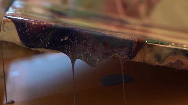 Beautiful paint drips off of the canvas.