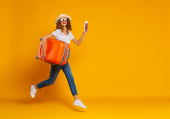 Fototapeta na wymiar concept of travel. happy woman girl with suitcase and passport on yellow background.