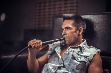 Sexy man exhales smoke in nightclub.