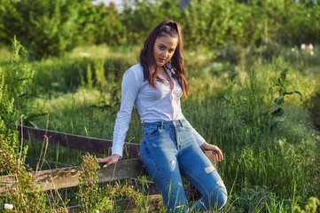 Outdoor portrait of a young girl in the countryside . The model is dressed in jeans and a white shirt