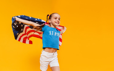 happy child girl with flag of   United States of America USA on yellow   background.